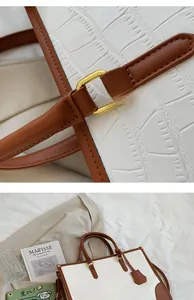 Close-up of white crocodile pattern tote bag with brown straps and gold metal hardware