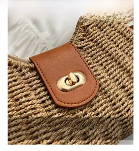 Macro shot of brown leather flap and golden twist lock on a hand-woven straw handbag