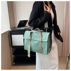 Detail of mint green canvas tote with wide strap and silver metal buckle on side