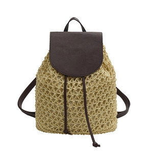 Straw woven backpack with brown leather trim and tassel accents for beach vacation