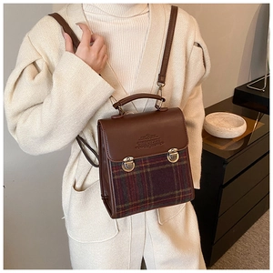 Detail of vintage brown leather and plaid fabric backpack with golden snap buttons