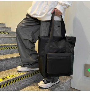 Detail of black nylon tote bag with front zipper pocket and multi-pocket functional design