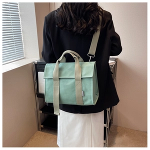 Detail of the mint green canvas tote bag showing the wide strap and crossbody style on a model