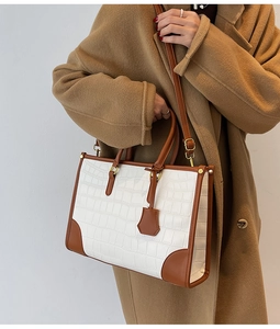 Detail of large tote bag with crocodile pattern and dual-tone brown leather trim