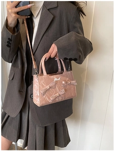 Detailsicht der rosa lackierten quadratischen Tasche mit Schleifen und Metallemblem