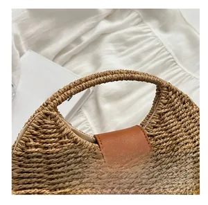 Detail of woven straw handbag featuring a brown leather strap and gold twist lock