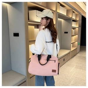 Pink oxford travel bag detail with leather logo patch and sturdy black shoulder strap