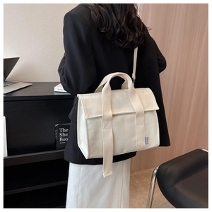 Detail showing white canvas tote bag with reinforced handles and brand tag for daily commute