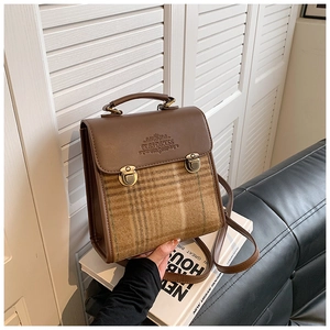 Detail of vintage brown leather and plaid fabric messenger bag with metal buckle