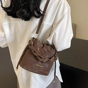 Braune gesteppte Beuteltasche mit geflochtenem Griff und verstellbarem Schultergurt