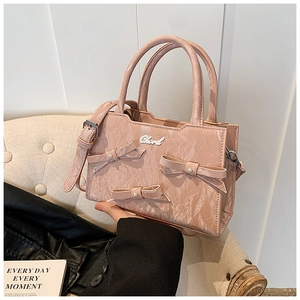 Detail der rosa Handtasche mit Marmorstruktur, dekorativen Schleifen und Perlenakzenten
