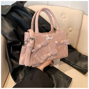 Rosa Handtasche mit Marmortextur und Schleifen vor einer schwarzen Lederjacke präsentiert