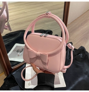 Detail of sweet pink handbag with 3D bow decoration and silver dual zippers