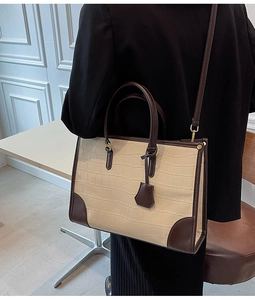 Detail of structured tote bag with crocodile pattern and stylish dark brown trim