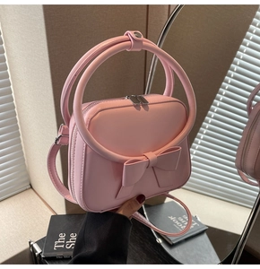 Detailed view of pink bow handbag with circular handle and dual zipper closure