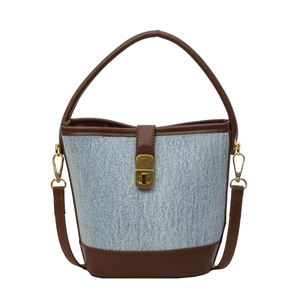 Blue denim bucket bag with brown leather trim and golden metal clasp in front view