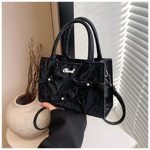 Detailansicht der schwarzen Falten-Handtasche mit Perlen-Schleifen und Metall-Logo