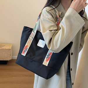 Black nylon tote bag with patterned shoulder strap shown in a lifestyle model shot
