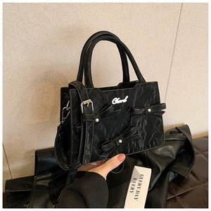 Details der schwarzen Handtasche mit Perlen-Schleifen und glänzender Wellenstruktur