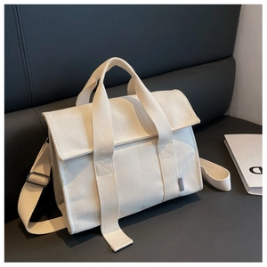 Detail of off-white canvas tote bag featuring reinforced straps and adjustable metal buckle