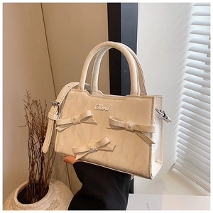 Detail einer weißen Ledertasche mit eleganten Schleifen und metallischem Logo
