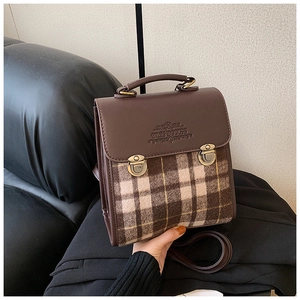 Detail of vintage plaid backpack showing embossed logo and bronze metallic buckles