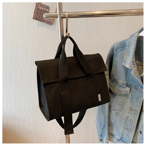 Detailed shot of black canvas tote bag hanging with sturdy wide straps and flap closure