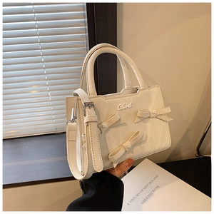 Detailansicht der cremefarbenen PU-Handtasche mit Schleifen und Silberbeschlägen