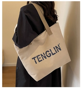 Detail of the durable canvas tote bag featuring comfortable wide shoulder straps and logo
