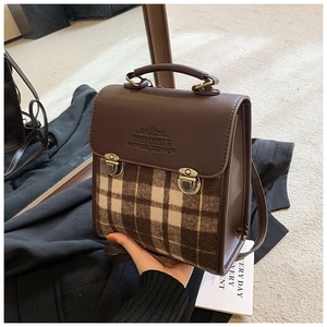 Detail view of vintage leather backpack featuring classic plaid fabric and bronze buckle