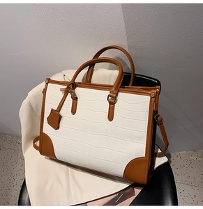 Detail of two-tone tote bag with crocodile texture and brown leather accents