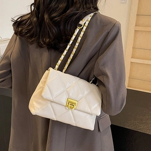 Quilted beige shoulder bag with gold chain strap shown on model in minimalist style