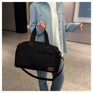 Detail of high-capacity black Oxford fabric travel bag with premium brown leather logo patch