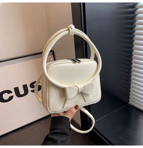 Detail of cream white handbag with bow decoration and circular metal handles