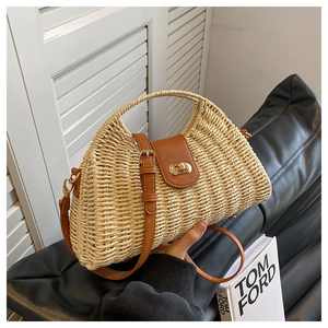 Detail of woven straw bag with brown leather trim and metallic twist lock closure