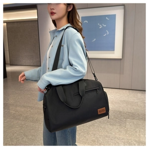 Detail of a large black Oxford travel bag with side zipper and leather brand logo