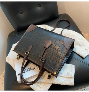 Close-up of crocodile textured tote bag with gold buckles on a stylish tweed background