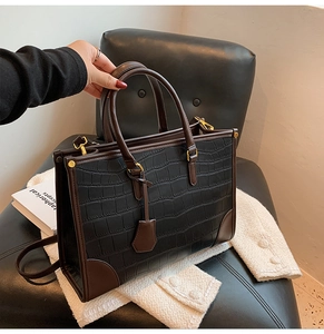 Close-up of black crocodile pattern leather tote bag with gold metal hardware details