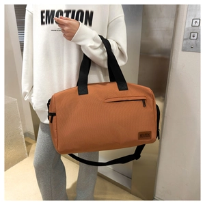 Detail of rust red canvas travel bag showing large capacity, double handles and branding