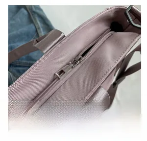 Detail of a purple nylon tote bag showing a smooth zipper and reinforced strap stitching