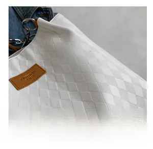 Detail of white quilted leather tote bag with leather logo tag and silver chain buckle