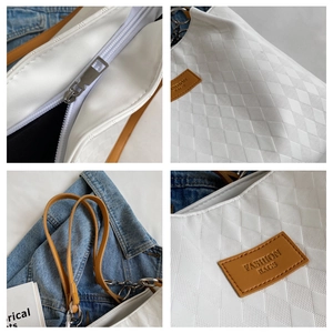 Detail of white quilted faux leather texture with brown strap and silver zipper closure