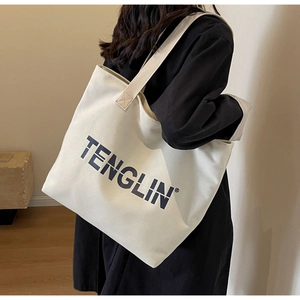 Close-up of the large canvas tote bag showing the black logo and premium texture