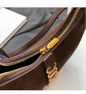 Detail of smooth gold zipper and suede texture on retro brown shoulder bag