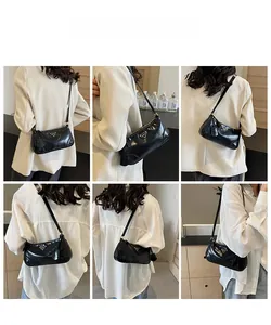 Detail shot of black glossy underarm bag with silver triangle hardware and minimalist finish