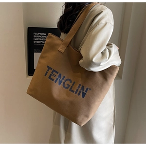 Large brown canvas tote bag shown on model highlighting its capacity and shoulder fit