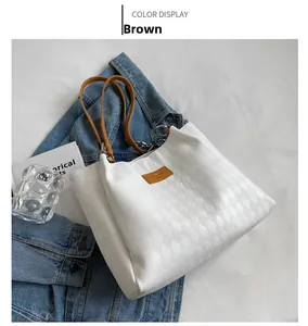 Macro shot of white quilted tote bag with brown leather straps and fashion branding