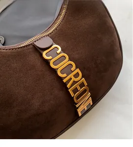 Detail shot of dark brown suede shoulder bag with gold metal COCREONE logo