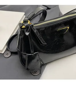 Detail of crinkled leather texture and gold-tone triangular logo on black shoulder bag