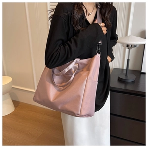 Detail of mauve nylon tote bag featuring side pockets and adjustable shoulder strap